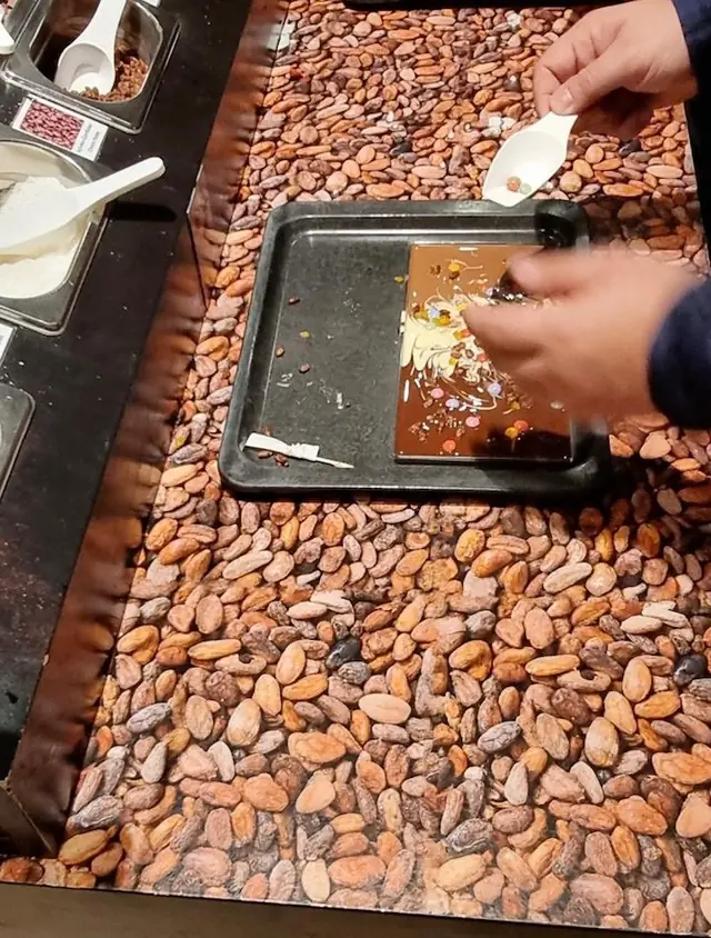 À la ChocoWelt, des visiteurs décorent leur propre tablette de chocolat avec des ingrédients au choix