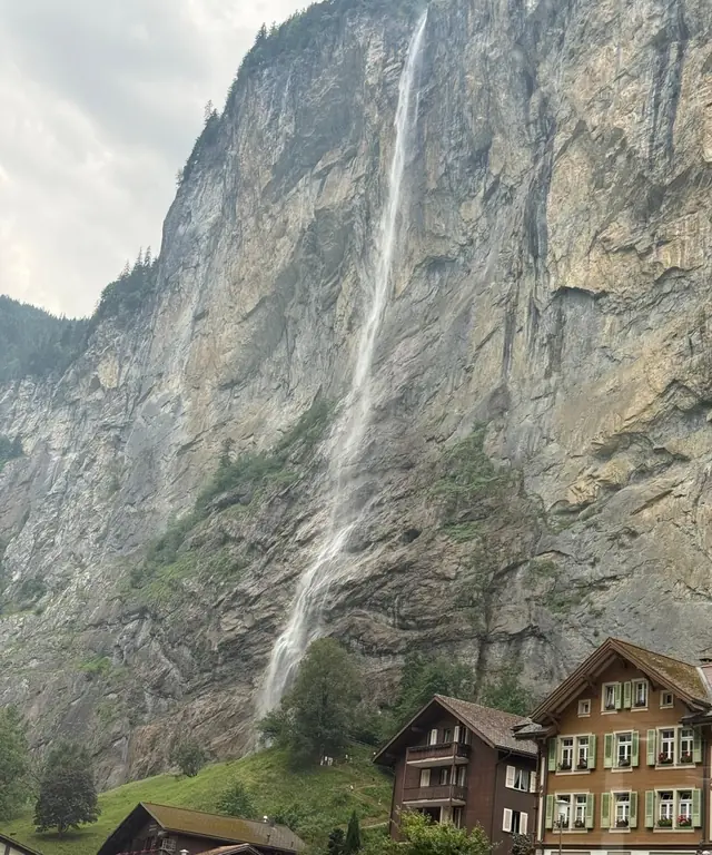 La chute du Staubbach dévale la paroi rocheuse derrière des chalets de Lauterbrunnen