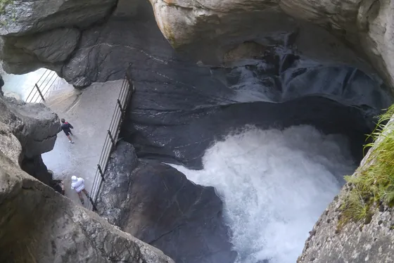 Passerelle pour visiteurs avec garde-corps au bord de l’eau écumante, dans la gorge rocheuse des chutes du Trümmelbach