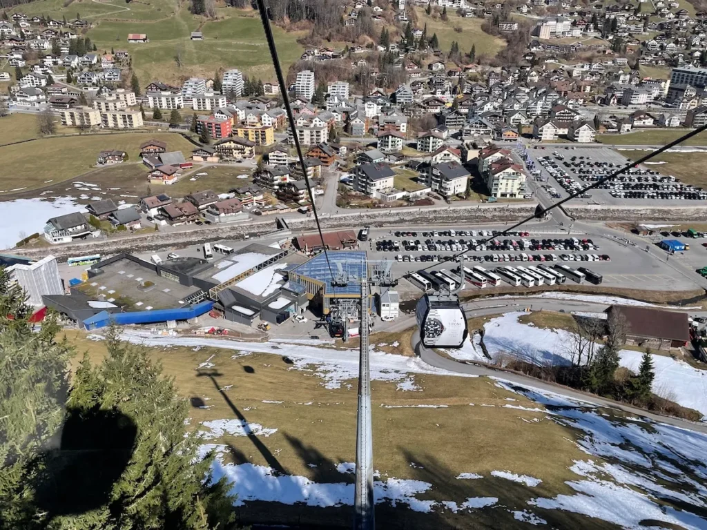 Luftaufnahme der Seilbahnstation in Engelberg mit Gondel, Parkplätzen und Dorfansicht im Tal – beliebte Route für den Transfer von Zürich nach Engelberg.