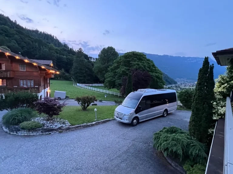 Silberner Mercedes-Benz Sprinter vor Schweizer Chalet-Hotel in Alpenlandschaft – SWIVON Firmenausflug-Transfer Zürich