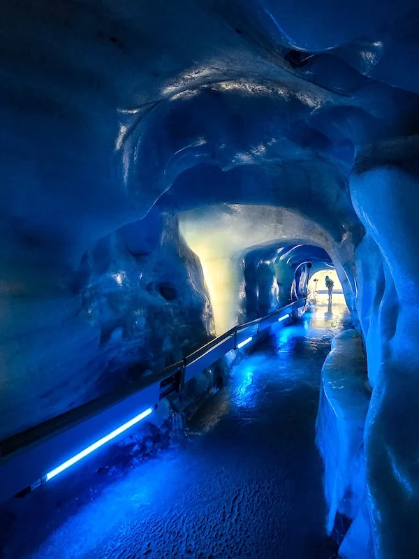 Blau beleuchteter Eispalast im Jungfraujoch mit kunstvoll geschnitzten Eiswänden – SWIVON Ausflugs-Transfer zur Jungfrau