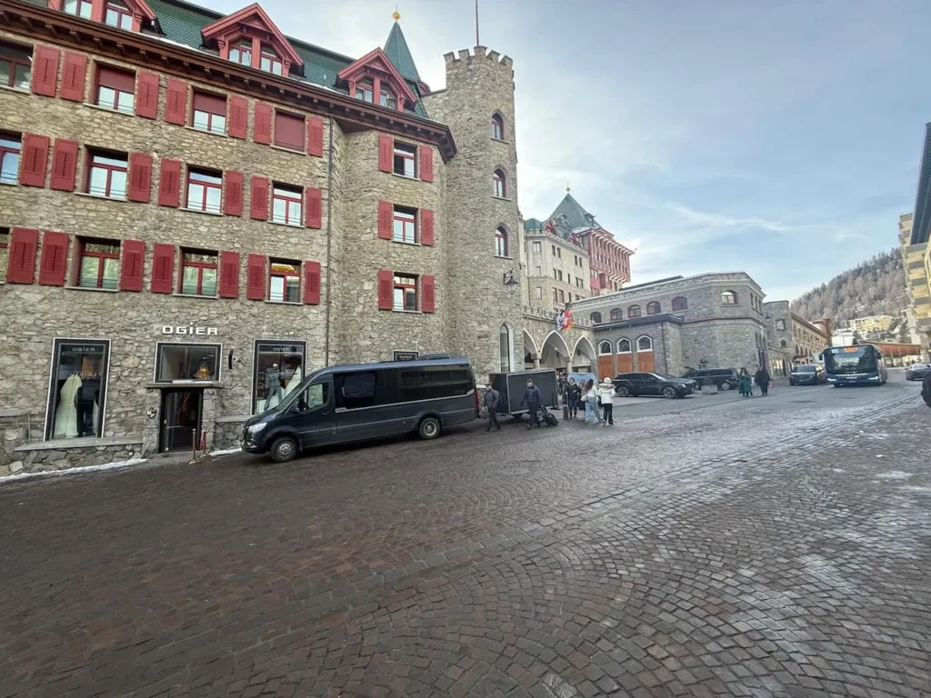 Hourly chauffeur service with black van in front of a historic building in a Swiss city, guests getting in and out.