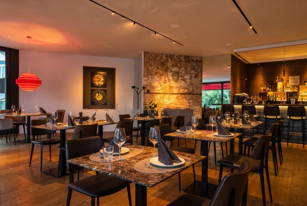 Birdy's by Achtien in Brunnen – modernes Restaurant mit Backsteinsäule, roter Designerlampe, Marmortischen und Bar, direkt am Vierwaldstättersee, Restaurant-Transfer ab Zürich mit Chauffeur