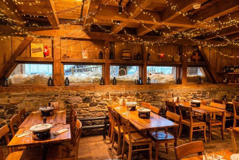 Chäsalp am Zürichberg – rustikale Gaststube mit Holzbalken, Lichterketten, Natursteinmauer und Fondue-Caquelons auf den Tischen, urchiges Schweizer Restaurant, Restaurant-Transfer ab Zürich mit Chauffeur