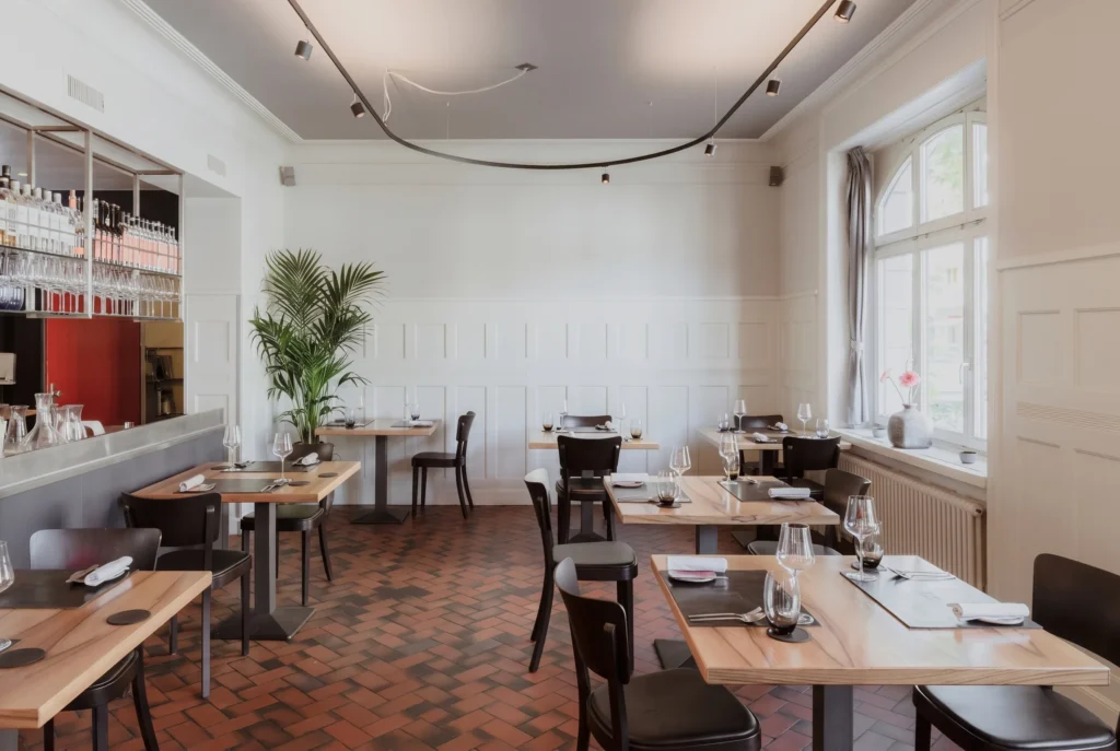 Restaurant EquiTable in Zürich – helles, reduziertes Interieur mit weisser Täferung, Terrakotta-Fischgrätboden und Weinregal, nachhaltiges Fine-Dining Restaurant im Kreis 4, Restaurant-Transfer ab Zürich mit Chauffeur