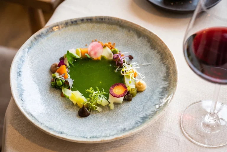 Grüner Gemüse-Sud mit buntem Gartengemüse, Kräutern und essbaren Blüten im Restaurant Roots in Basel, kreative Spitzenküche, Fahrt ab Zürich mit Chauffeur