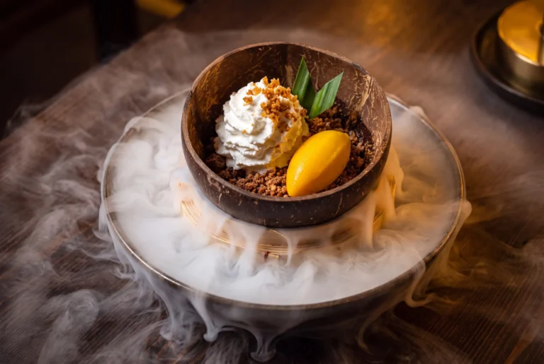 Asiatisches Dessert in der Kokosschale mit Mango-Sorbet, Rahm und Trockeneis-Nebel im Spices Kitchen & Terrace am Bürgenstock, Restaurant-Transfer ab Zürich mit Chauffeur