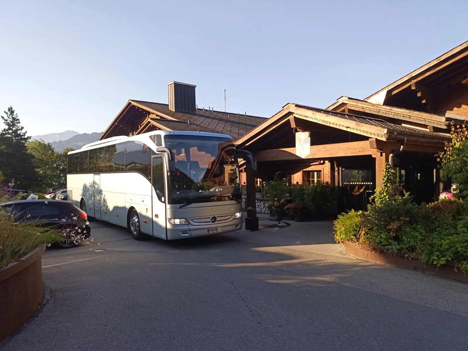 Hochzeits-Shuttle in Zürich – Mercedes Reisebus (Car) mit Chauffeur vor einer Chalet-Hochzeitslocation in den Bergen