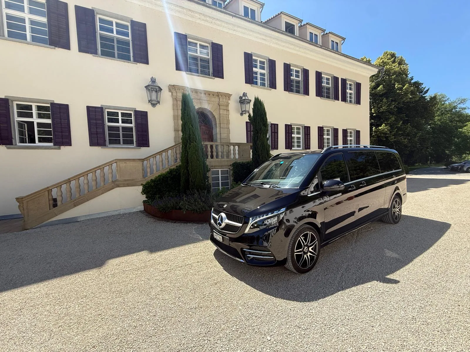 Hochzeitsauto mieten in Zürich – schwarze Mercedes V-Klasse vor einer herrschaftlichen Hochzeitslocation mit Kiesvorplatz
